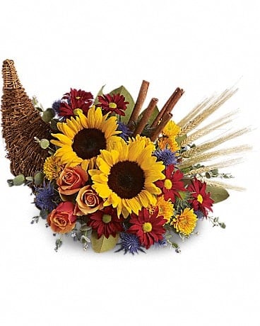 Classic Cornucopia Classic Cornucopia - Along with joy, this cornucopia carries an abundance of beautiful fall flowers and foliage. A stunning centerpiece or inviting entryway display, this beauty will be at home anywhere in the house. Dazzling sunflowers, light orange roses and spray roses, red daisy spray chrysanthemums, yellow cushion spray chrysanthemums, eucalyptus, magnolia leaves, cinnamon sticks and wheat are perfectly arranged in a wicker cornucopia. Now you know why cornucopia translates to "horn of plenty."