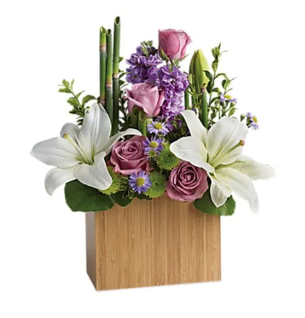Kissed With Bliss by Teleflora Kissed With Bliss by Teleflora - An elegant way to show you care, this bit of bliss blends luxurious lavender roses with wondrous white lilies into a stunning floral sculpture. Accented with exotic greens and presented in a modern bamboo rectangular vase, it brings natural serenity to any space. Includes lavender roses, white asiatic lilies, lavender stock, monte cassino asters and green chrysanthemums, accented with fresh greenery. Delivered in a large Bamboo Rectangular vase.
