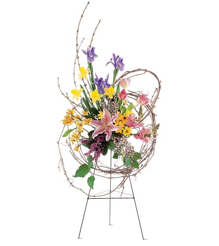 Circle of Peace -  This beautiful easel spray with its unique collection of spring blossoms will spread a message of peace to all.  Each spray contains circles of grapevine intertwined with tulips, iris, daffodils, lilies and alstroemeria, and is presented on an easel. Approximately 30&quot; W x 46&quot; H 