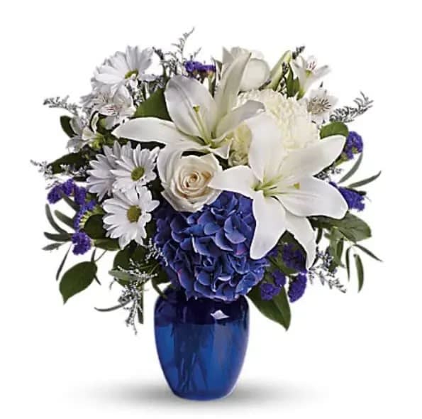 Beautiful In Blue - In this arrangement, the serenity of the color blue along with the purity of intention symbolized by white will let the family know you are sending your calm strength to them during these difficult times. Beautiful blooms such as blue hydrangea, crème roses, white lilies and alstroemeria along with yellow and white chrysanthemums, eucalyptus, limonium and more are beautifully arranged in a dazzling cobalt blue vase.   Orientation : One-Sided  All prices in USD ($)  Standard  T209-3A  Deluxe  T209-3B  Premium  T209-3C