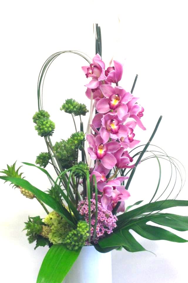 Exotic Paradise  - This Beatiful arrangement of pink cymbidium with mini pineaple and green hydrangeas arranged in a white cristal vase is a very beautiful way to show that person you care deeply for them.
