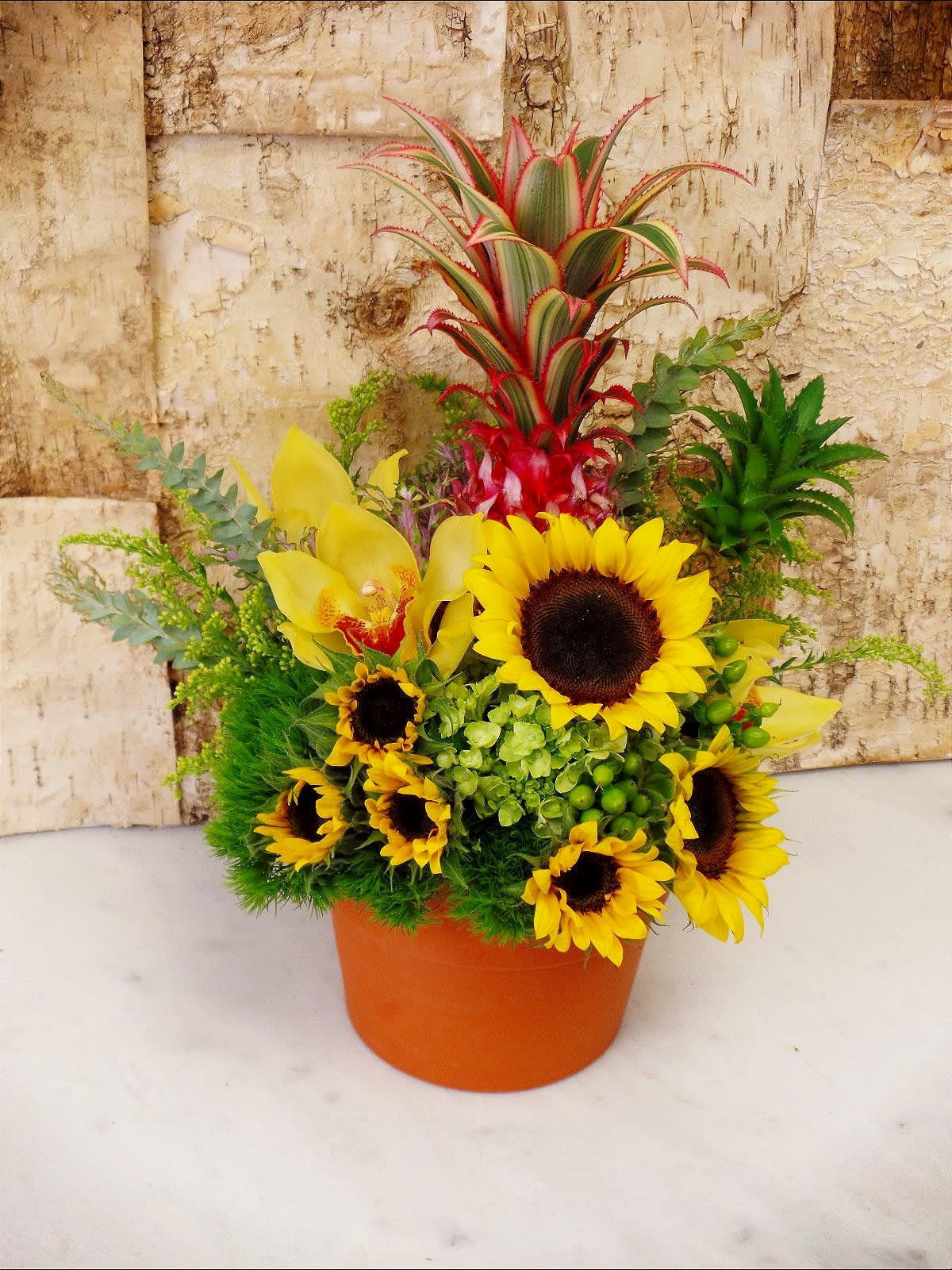 Pineapple Bouquet Pineapple Bouquet - Mini- sunflowers in a terracotta pot with Mini-pineapples and orchids.