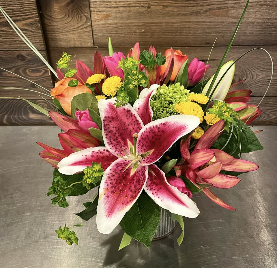 Stargazer Surprise  Stargazer Surprise  - A colorful mix of  hot pinks, reds, yellows, oranges and lime green flowers including stargazer lilies, hydrangea, lecadendron, roses, tulips, and button poms in a galvanized container.  Approx. 10" Tall x 8" Wide