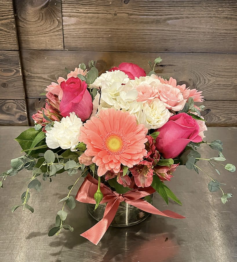 Sweet Beginnings  Sweet Beginnings  - In short cylinder vase a mix of pink and white flowers including hydrangea, gerebera daisies, roses, spray roses, alstromeria and carnations accented with minimal greenery.  Approx. 10" Tall x 9" Wide