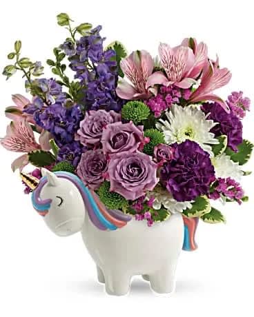 Teleflora's Magical Mood Unicorn Bouquet - With her golden horn and hand-painted details, this charming ceramic unicorn makes a magical presentation of this lovely lavender bouquet! This magical gift features lavender spray roses, pink alstroemeria, fuchsia carnations, purple larkspur, white cushion spray chrysanthemums, green button spray chrysanthemums, raspberry sinuata statice, and variegated pittosporum. Delivered in a Charmed Unicorn Keepsake. 