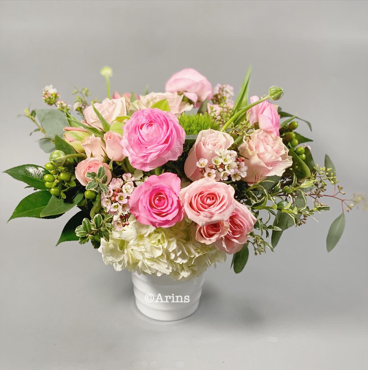 Bonita -  This lush, adorable arrangement is pink roses, spray roses, and greenery in a white ceramic vase.  