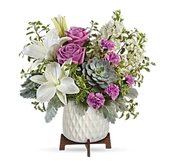 Teleflora's Garden Oasis Bouquet - &quot;Straight out of a mid-century design magazine, this chic planter is the perfect vessel for wondrous white lilies, lavender roses and a stunning living succulent plant. This gorgeous bouquet includes lavender roses, white asiatic lilies, miniature lavender carnations, white stock, pitta negra, dusty miller, and a large echeveria succulent plant. Delivered in a Mid Mod Geometric Planter.   Orientation : One-Sided  All prices in USD ($)  Standard  TEV58-8A  Deluxe  TEV58-8B  Premium  TEV58-8C&quot;