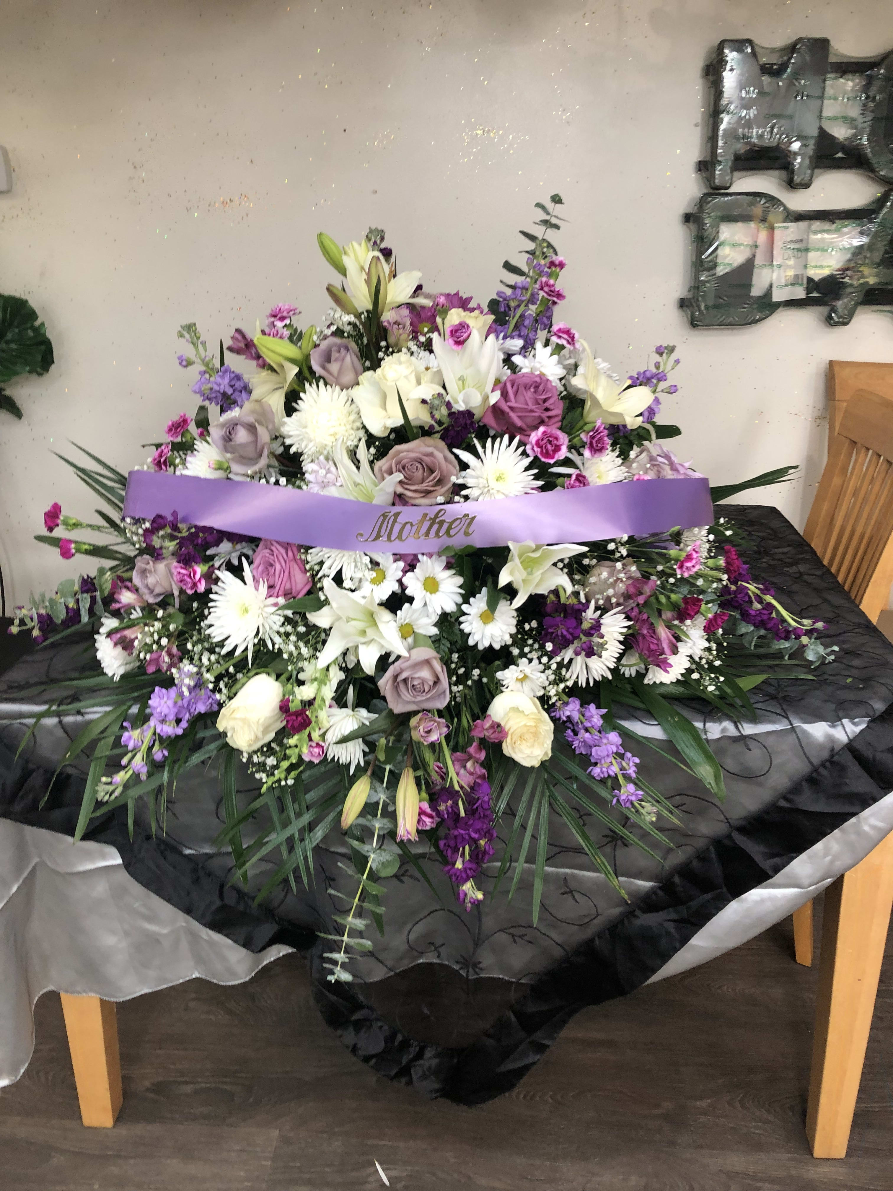 Purple and white casket. Purple and white casket. - Roses, lily's, stock, spiders, monte casino, daisy's, carnations, baby's breath and greenery.