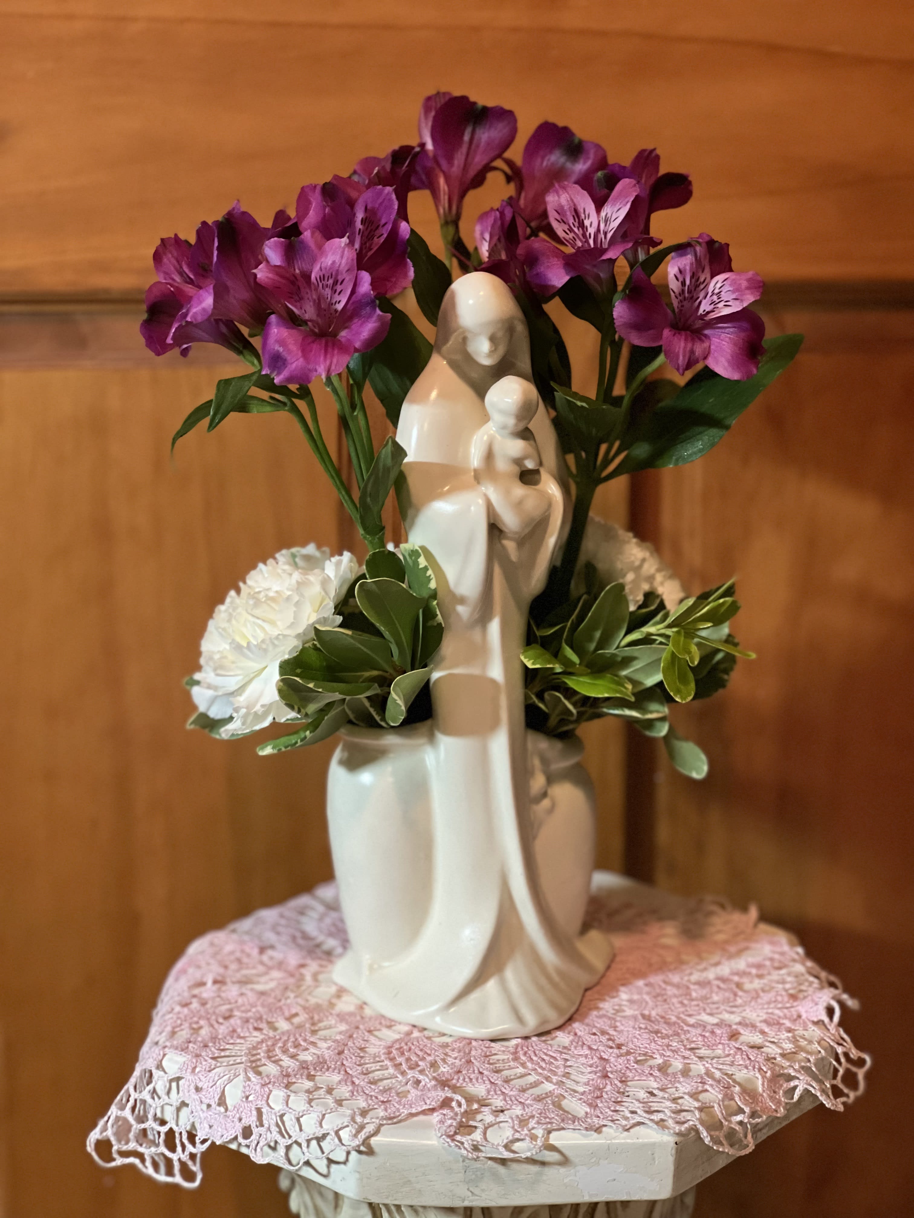 Madonna with Flowers - Beautiful Blooms for a beautiful statue.  Madonna holding child surrounded by purple Alstroemerias and white Carnations. Can be reused as a planter or vase. Sure to be a keepsake after the flowers had faded. Statuary over 11&quot; tall. (only 1 available)