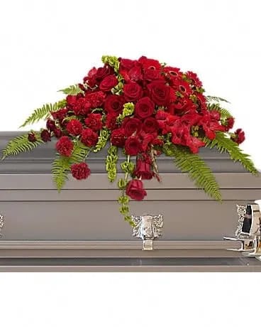 Red Rose Sanctuary Casket Spray - A gorgeous mix of dazzling red flowers will make a grand, yet graceful impression. Beautiful red roses, spray roses, gerberas, gladioli and carnations along with vibrant green bells of Ireland create a sincere tribute. 