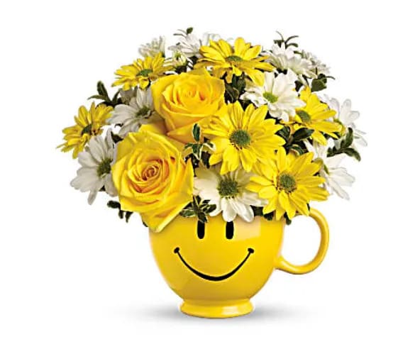 Teleflora's Be HappyÂ® Bouquet with Roses - There are probably a million reasons this is such a popular bouquet. Of course, there are probably just as many reasons to send this cheerful arrangement. Full of happy flowers, this ceramic happy face mug will bring smiles for years to come. Especially when filled with that first cup of morning coffee or cocoa! Yellow roses and daisy spray chrysanthemums along with white daisy spray chrysanthemums and oregonia are delivered in the one and only Be HappyÂ® mug. 