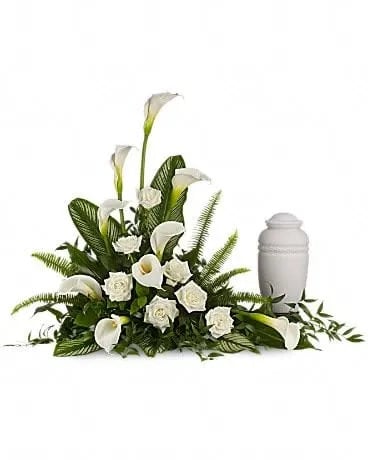 Stately Lilies - A calming portrait in ivory. Majestic calla lilies and stately white roses are framed by the lush leaves of aspidistra and calathea. Soft green sword fern adds to the soothing tones. Large white calla lilies pair with white roses and lush greens that include soft, airy sword fern and glossy aspidistra. Please note: Arrangement does not include urn. 