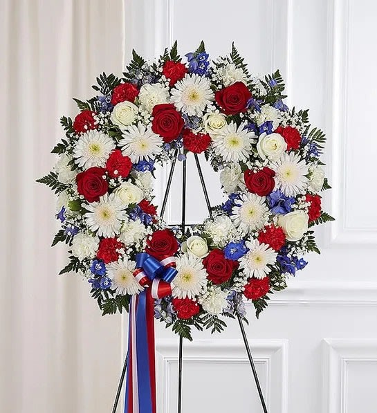 Serene Blessings™ Red, White &amp; Blue Standing Wreath - They served their country with honor and pride, so it’s only fitting to honor them with a beautiful symbol of eternal life. Our patriotic standing wreath arrangement is meticulously crafted by our expert florists to honor a brave veteran who has passed away. Filled with lush blooms in red, white and blue, it’s a fitting final tribute for the funeral services.  •Appropriate for the funeral home  •Easel may not be available in all areas  •Our florists hand-design each arrangement, so colors and assortment may vary based on local availability