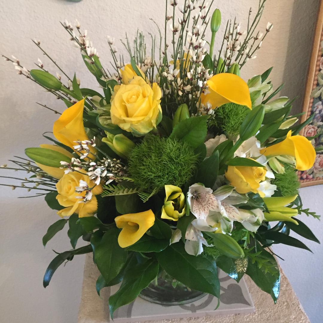 Yellow and White Vased Arrangement - A selection of the season's best varieties for a sunshiny color scheme. Brighten someone's day with this cheerful color palette. Individual varieties will vary by season. This is an all around design that works well in the center of a table. 