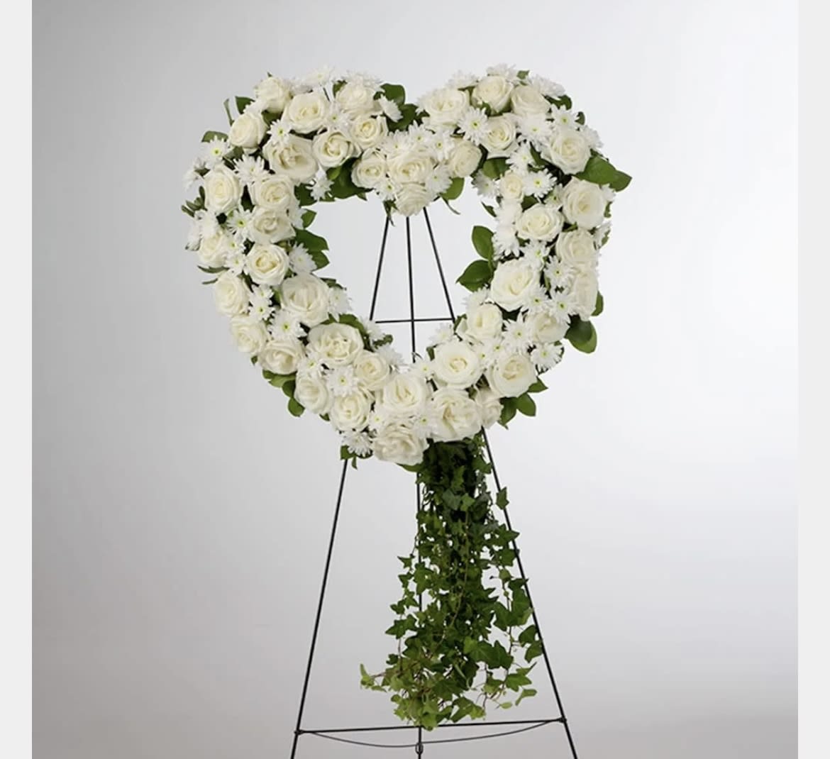 Love in our Hearts by BloomNation™ Love in our Hearts by BloomNation™ - An all white tribute, this heart shaped easel shows your everlasting love. Featuring a variety of white flowers and greenery, this heart with a trail of ivy compliments the beauty of life.