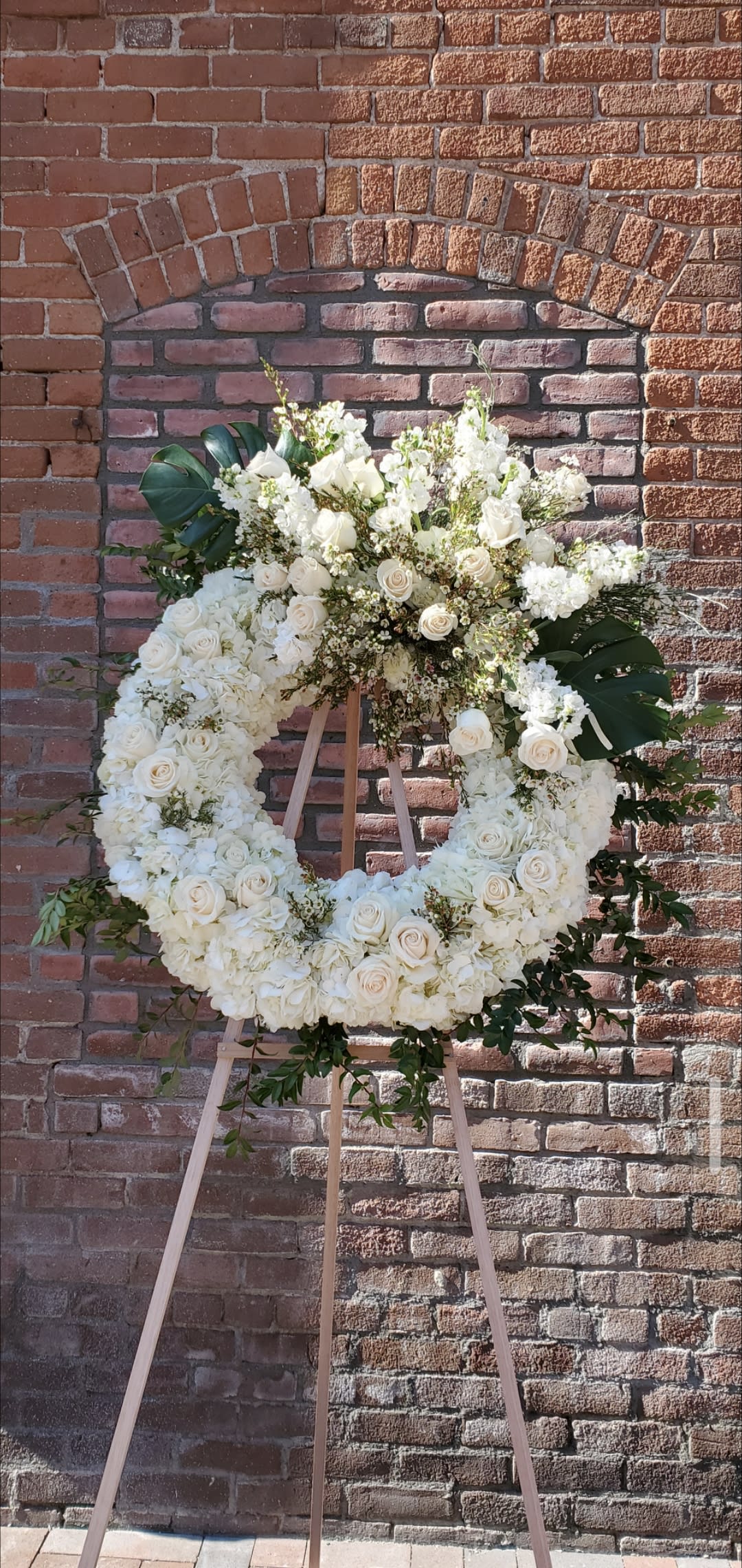 Serenity wreath Serenity wreath - An all white standing wreath composed of hydrangea, white roses, mixed monstera leaf and mixed greens with fillers