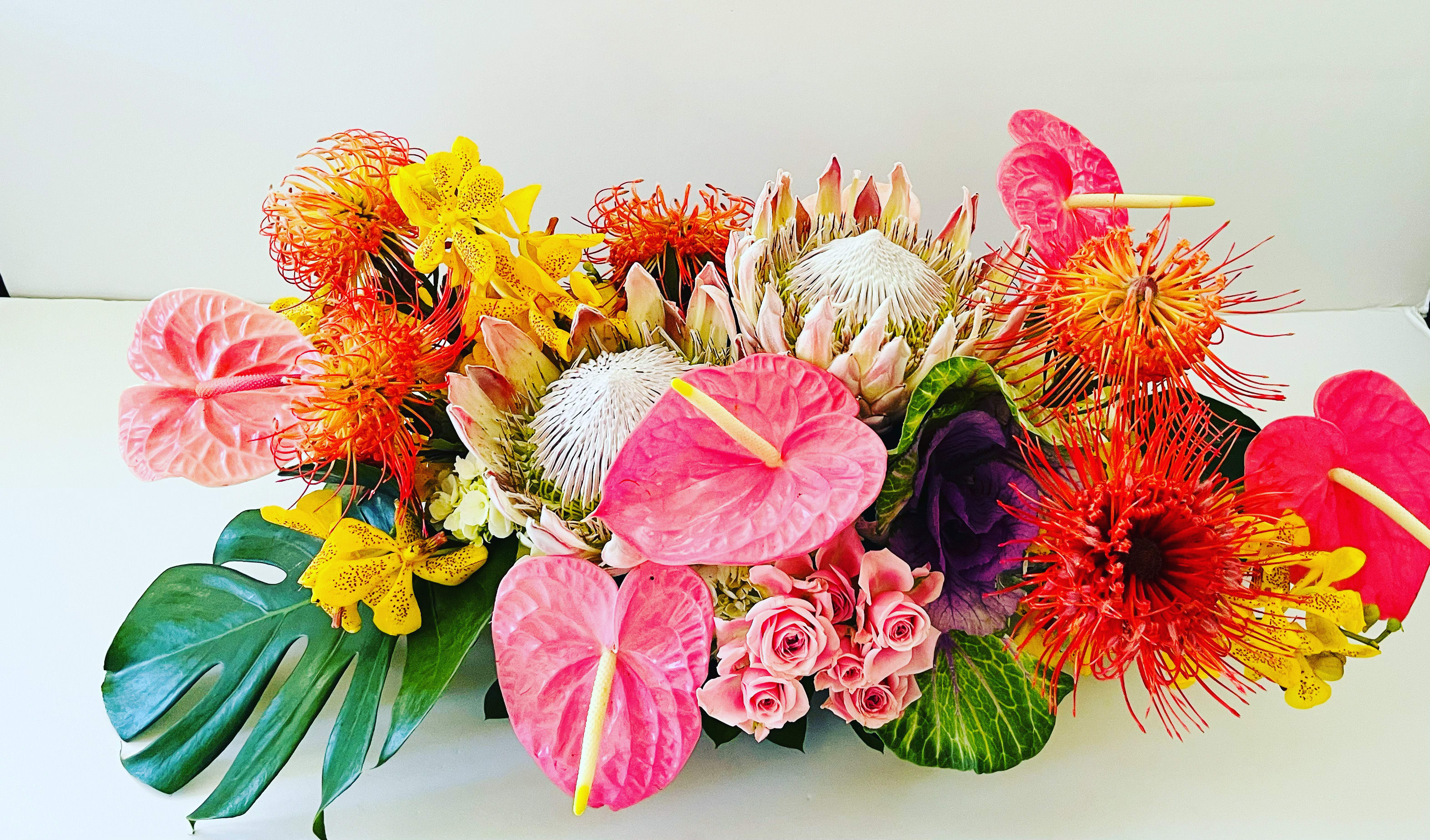 The perfect centerpiece  - A combination of Vibrant tropical foliage, a hint of garden blooms and tropical blooms. The perfect display for any occasion.   Please contact us directly for any custom orders or requests info@helemelebotanicals.com or 808.226.7667.  We are committed to malama 'aina and strive to use locally sourced material, reduce packaging and reuse and recycle where possible. We will pick up any of our product (vessels, plants and floral supply material) when delivering a subsequent order. At that time, a $5 credit toward future purchase will be issued for each ceramic, metal or wood vessel returned.