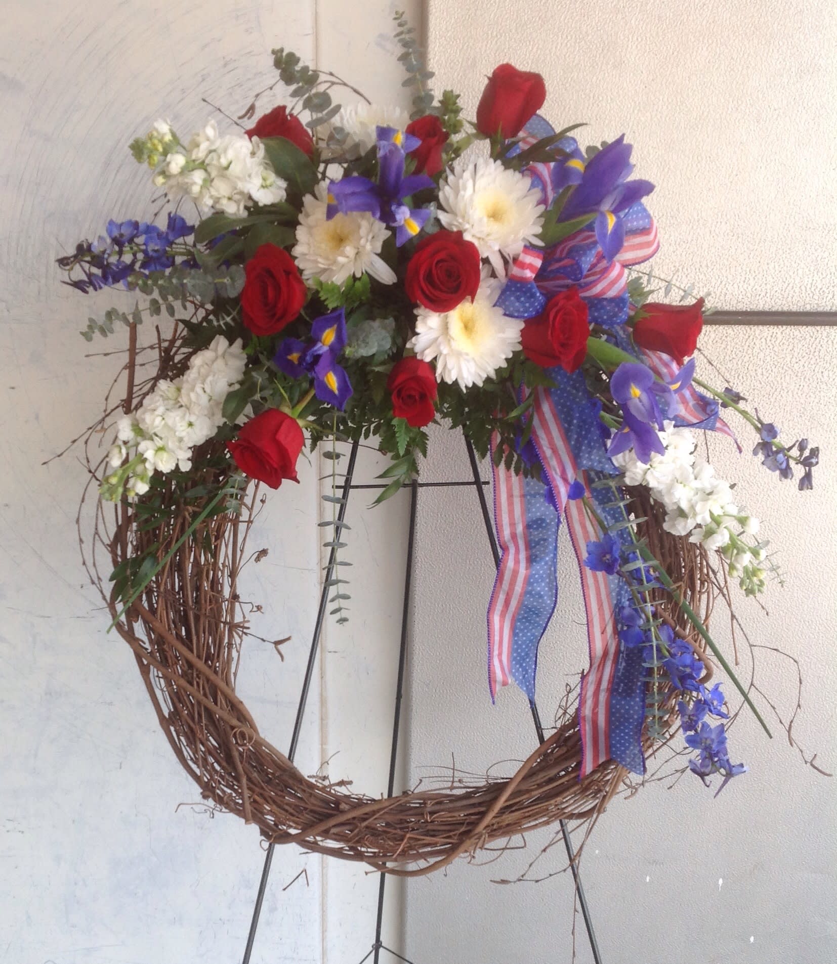 Patriotic Grapevine Wreath - Nice grapevine wreath on an easel designed with red, white &amp; blue flowers. Great for paying tribute to a serviceman or woman. 