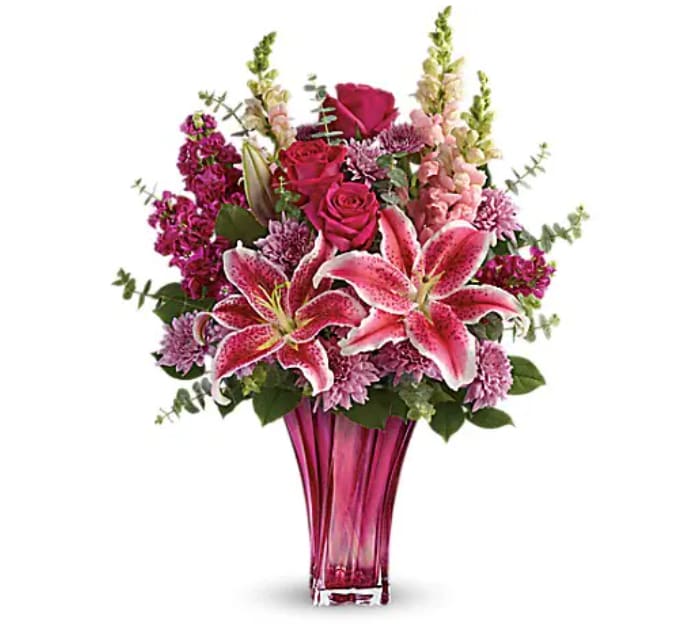 Teleflora's Bold Elegance Bouquet - When only the best will do for Mother's Day, surprise her with this incredible gift! Large and lush, this bouquet of hot pink roses, pink stargazer lilies and lavender mums is fragrant, feminine and fabulous. What an unforgettable treat when hand-delivered in this exquisite blown glass vase! This elegant bouquet features hot pink roses, pink stargazer lilies, burgundy stock, lavender cushion spray chrysanthemums, pink snapdragons, spiral eucalyptus, and lemon leaf. Delivered in a Bold Elegance vase.   Orientation : All-Around  All prices in USD ($)  Due to seasonal price increase on flowers, our prices will reflect an increase for this holiday on certain delivery dates.  Standard  TEV52-1A  Deluxe  TEV52-1B  Premium  TEV52-1C