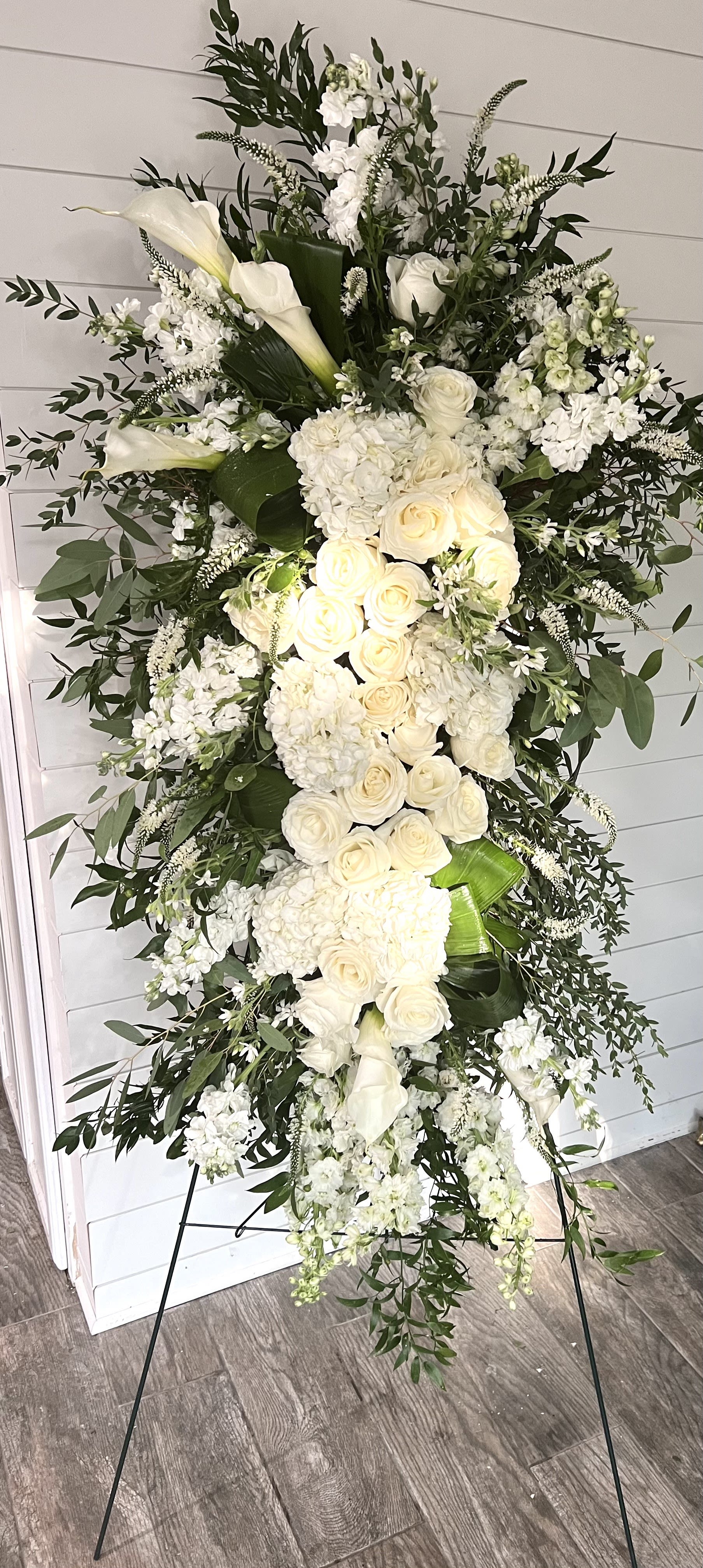 Premium Funeral Spray - Honor your loved one with a funeral spray of white premium roses, delphinium, stock, hydrangea,calla lilies, and assorted white fillers and designer greenery. Displayed on a 60 inch wire easel.