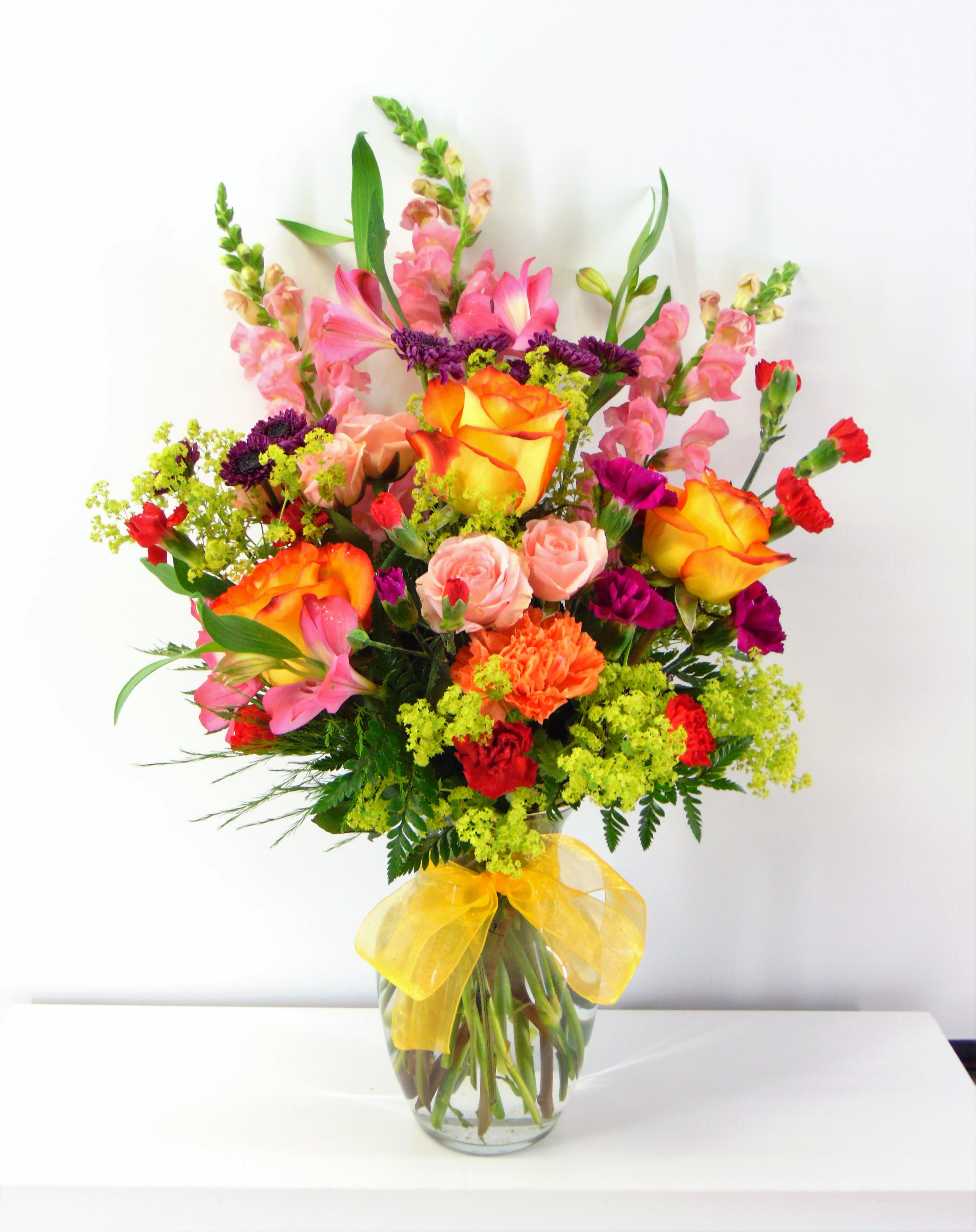 Sweet Surprise - A surprising color combination or yellow-bicolor roses, pink snapdragons, burgandy carnations, pink roses and yellow, purple, red, orange and pink accents. Surprise someone special today.  Deluxe option is pictured.