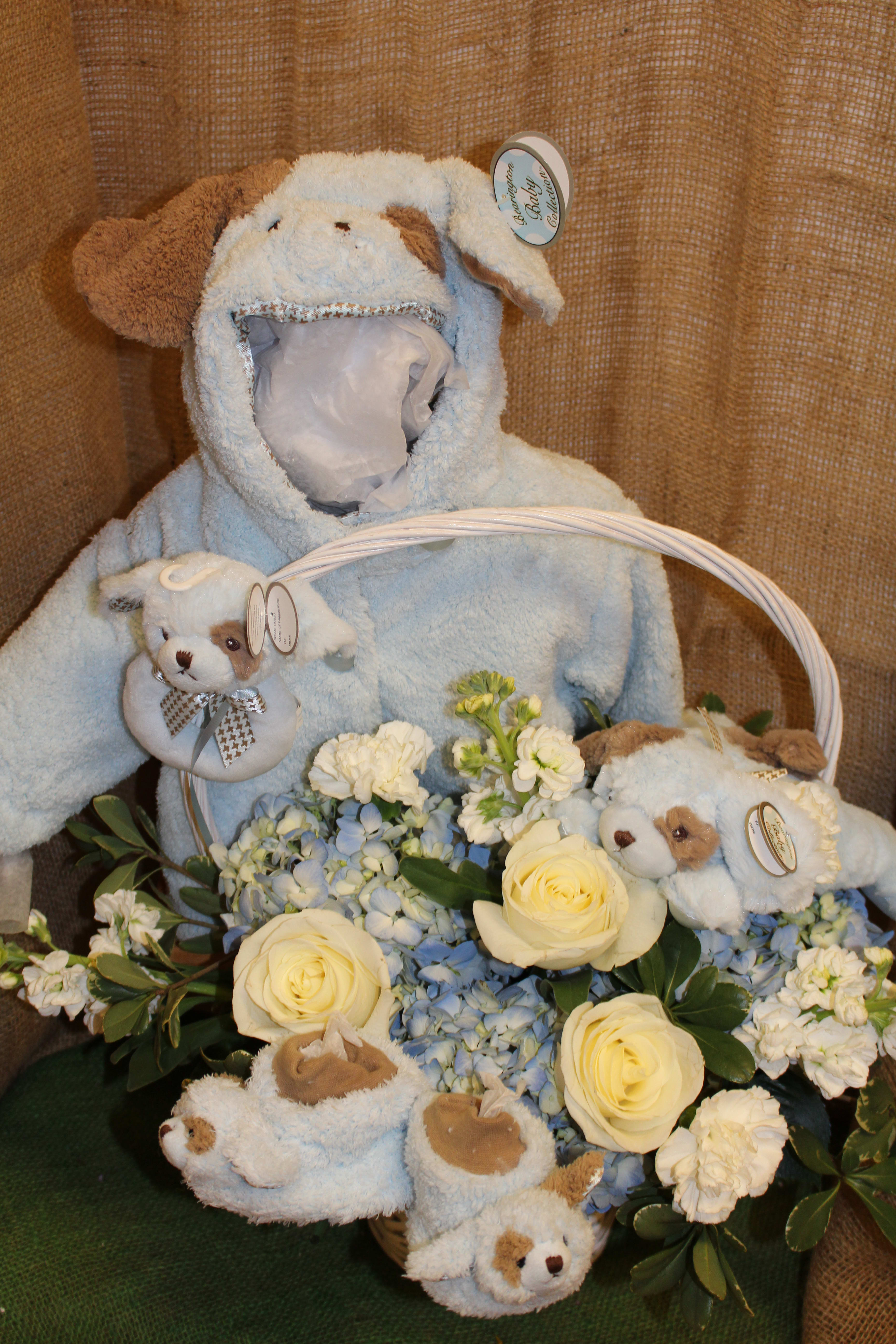 Warm and Fuzzy - Keep the newest addition in your life feeling warm and fuzzy with this ensemble! A basket of fresh flowers surrounded by his future favorite things! A warm jacket with a puppy hood, matching booties, rattle, and puppy pal are best sent surrounded by this arrangement of hydrangea, roses, carnations, and stock.