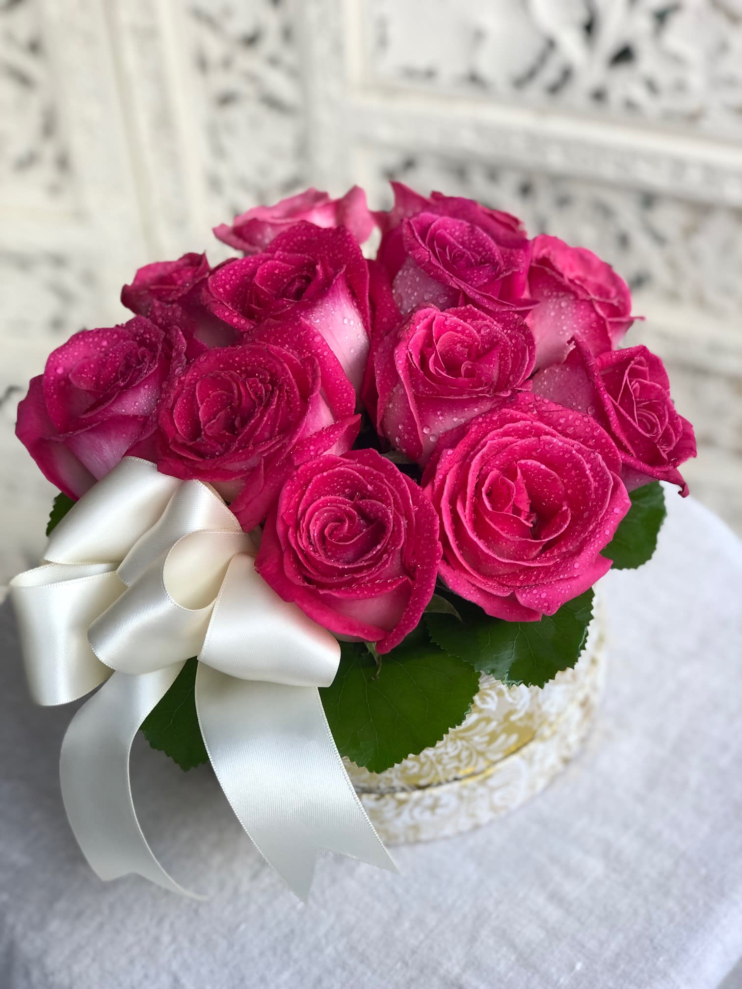 Pink Rose Box - Gorgeous pink roses presented in a gold and white box and simply accented with minimal greens and a satin bow. Please specify one dozen or two dozen and your preference for either classic ivory or sophisticated black satin ribbon. Perfectly elegant!