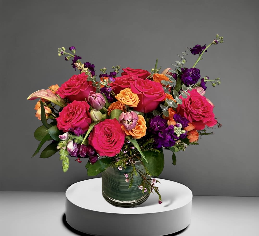Pop of Color - A bright colorful mix of roses, tulips, stock, and mini calla lilies arranged in a glass vase. The beautiful jewel toned flowers make an impressive gift.