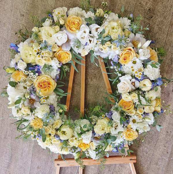Celebration of Life Celebration of Life - A standing 24 inch diameter Wreath on a wooden easel (included) that includes premium flowers like delphinium, lisianthus and garden roses. Substitutions can be made in color preference.