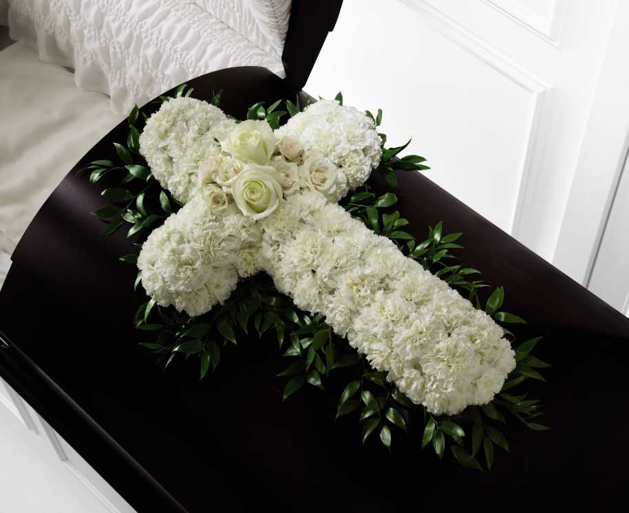 The FTD Peaceful Memories Casket Spray - The FTD Peaceful Memories Casket Spray is a gorgeous way to commemorate the faith and devotion of the deceased. White carnations are arranged in the shape of a cross accented in the middle with white roses and spray roses and along the sides with lush greens to create a lovely casket spray that brings peace and solace to those that attend their final farewell.