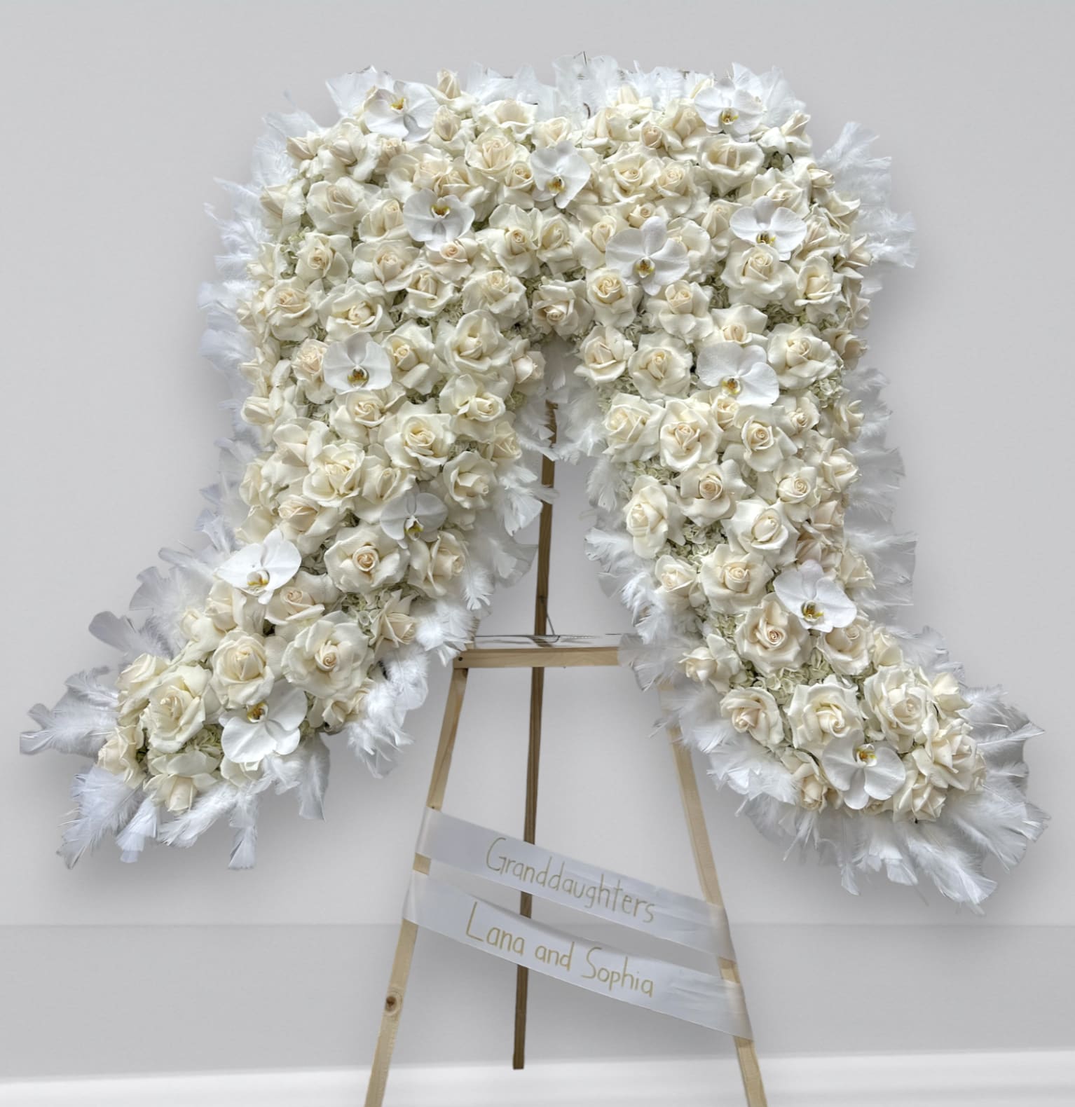 Angel Wingz - A beautiful funeral arrangement filled with hydrangea, roses and orchids. The arrangement has feathers around the arrangement giving it the wings feature. 