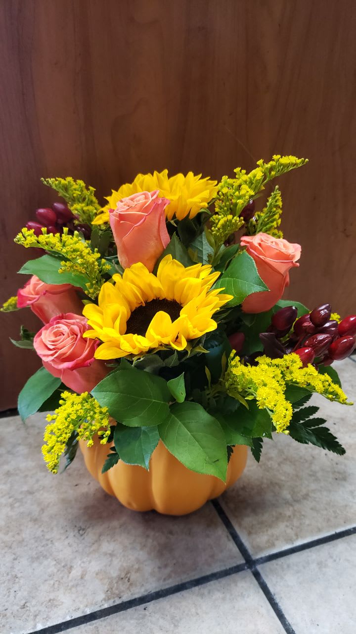 Seasonal Pumpkin    - A seasonal pretty pumpkin, with  2 medium sunflowers, 4oranges roses, 2 esteems of yellow  solid aster, 3 stems of   red hypericum with a ceramic  pumpkin container.