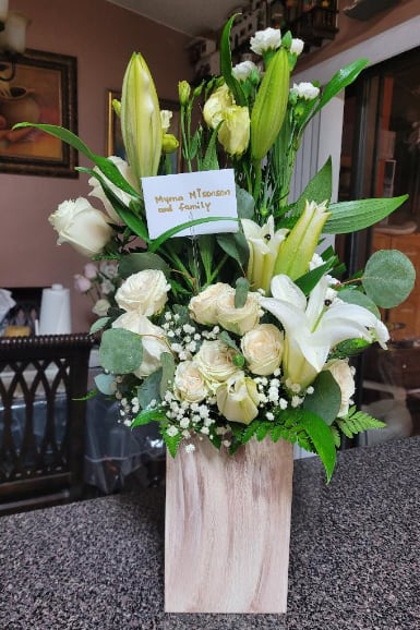 ETERNITY - Beautiful offering of love, to show your condolences, a composition of roses, carnations and white lilies with beautiful foliage, on a tall wooden base