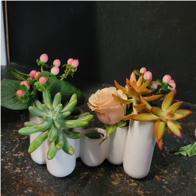Interest - Interesting presentation of textural flowers and succulents arranged in an equally interesting vase.