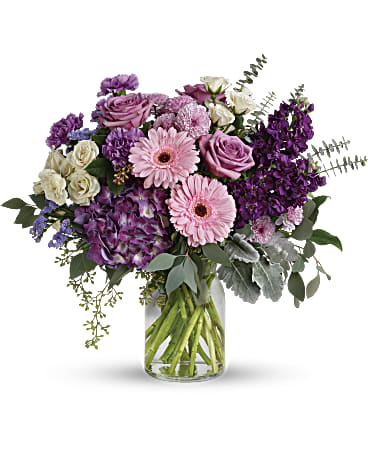 Magnificent Mauves Bouquet - Bring beauty to any occasion with the deep purples and playful pinks of this breathtaking bouquet. This magnificent bouquet features purple hydrangea, lavender roses, crème spray roses, pink gerberas, lavender carnations, purple stock, lavender cushion spray chrysanthemums, lavender sinuata statice, dusty miller, spiral eucalyptus, seeded eucalyptus, silver dollar eucalyptus, and lemon leaf. Delivered in a clear milk jug vase. Orientation: All-Around