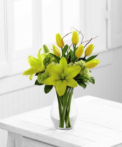 Your Day Bouquet - A bright and sunny display set to uplift their spirits with each exquisite bloom. Yellow tulips and Asiatic lilies are arranged among green mini hydrangea, lush greens and a curly willow accent. Seated in a classic clear glass vase this brilliant bouquet is a warm way to send your sweetest sentiments.  