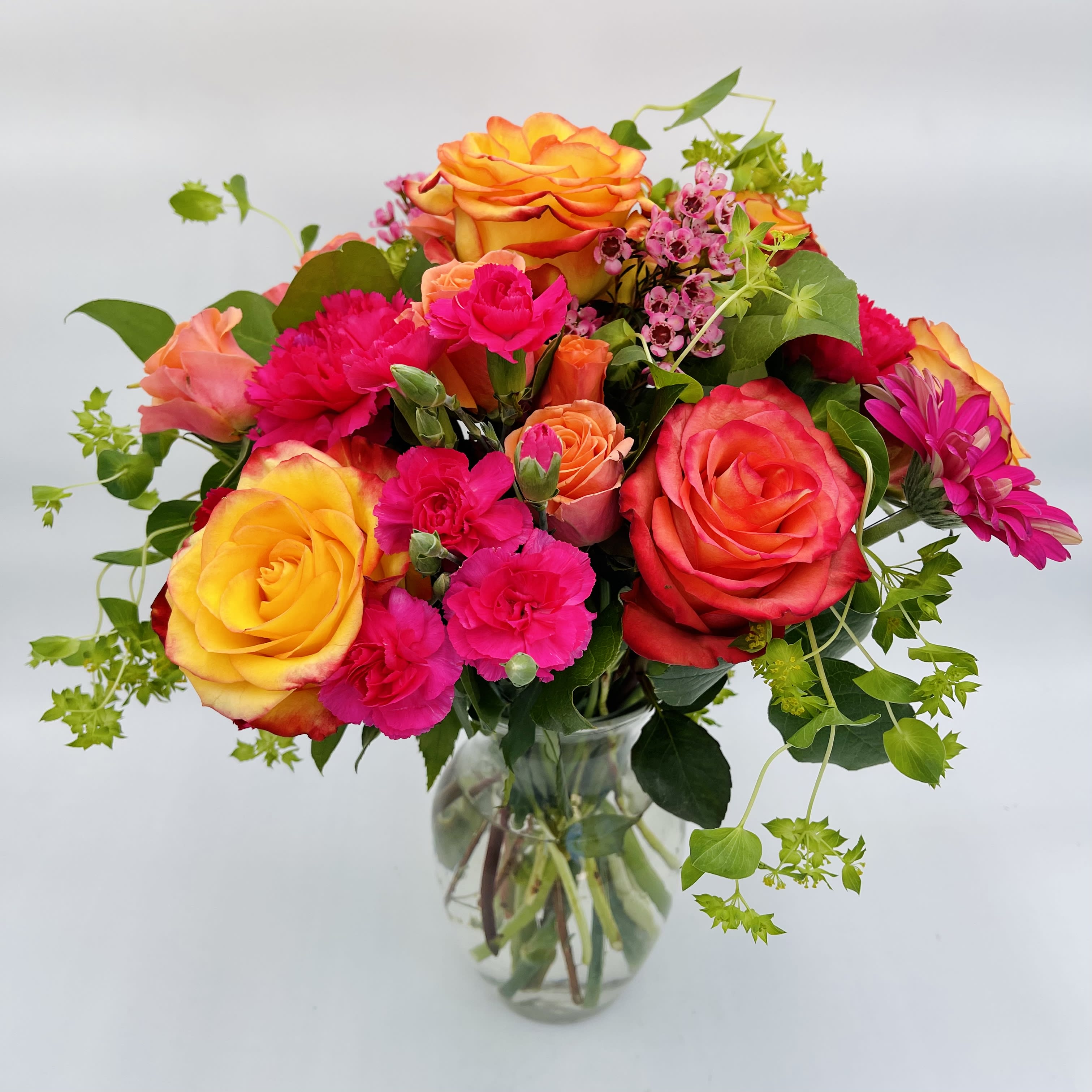 Passion Sunrise - This bouquet is perfect for bringing a splash of color to any room.  Perfect for celebrations and loved ones.  Arrangement includes roses, carnations, gerbera daisies, waxflowers, and assorted greenery in a clear glass vase.  Our florists handcraft your arrangements to be as fresh as possible, so certain flower varieties and colors may vary depending on availability.
