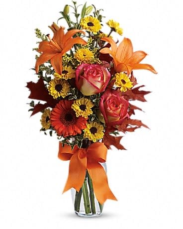 Burst of Autumn - A burst of beauteous blooms in autumn shades of orange and yellow is mixed with a handful of oak leaves, then delivered in a clear glass vase adorned with a bright satin ribbon. A splendid gift for birthdays or any fall occasion. A mix of fresh flowers such as Asiatic lilies, Viking spray chrysanthemums, roses and a miniature gerbera - in shades of orange and yellow - is arranged with preserved oak leaves in a clear glass vase adorned with an orange satin ribbon.