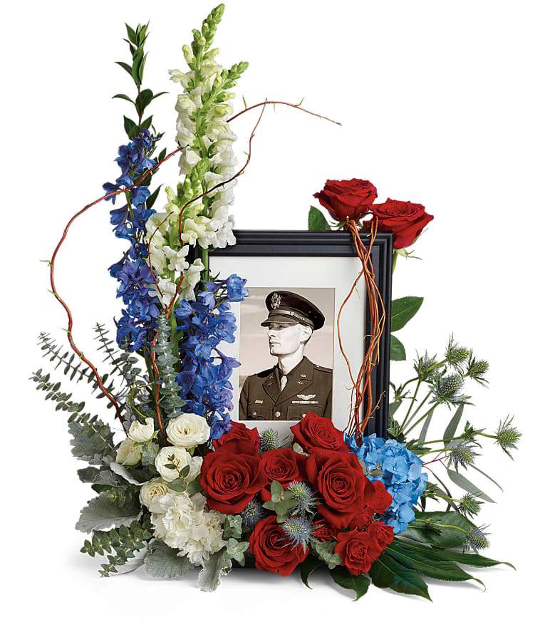 Always With Us Photo Tribute Bouquet - Honor the memory of an always-beloved with this beautiful display bouquet. Designed to surround a favorite photo, its patriotic mix of blue hydrangea with red and white roses is a respectful tribute. This bouquet features blue hydrangea, red roses, red spray roses, white spray roses, white carnations, blue delphinium, white snapdragons, blue eryngium, dusty miller, curly willow, spiral eucalyptus, parvifolia eucalyptus, aralia leaf and lemon leaf. Arrangement does not include picture frame. Approximately 22 1/2&quot; W x 25 1/2&quot; H