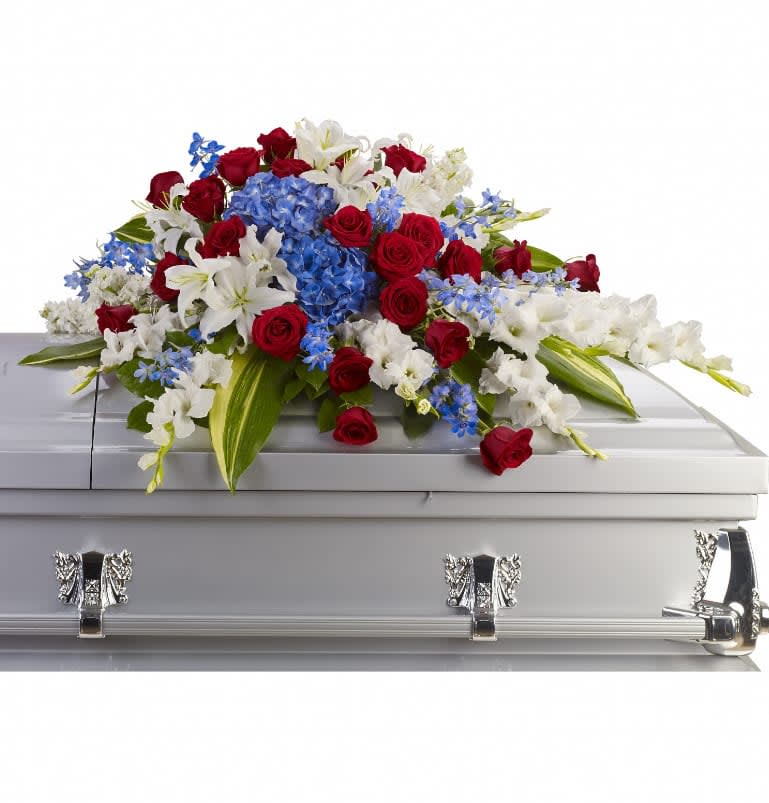 Distinguished Service Casket Spray - A beautifully patriotic way to pay tribute to a loved one. This half-couch spray sends an eloquent message of strength, respect and freedom. Brilliant flowers such as blue hydrangea, red roses, white oriental lilies and much more create this dignified way to honor the deceased. Approximately 46 1/2&quot; W x 24&quot; H
