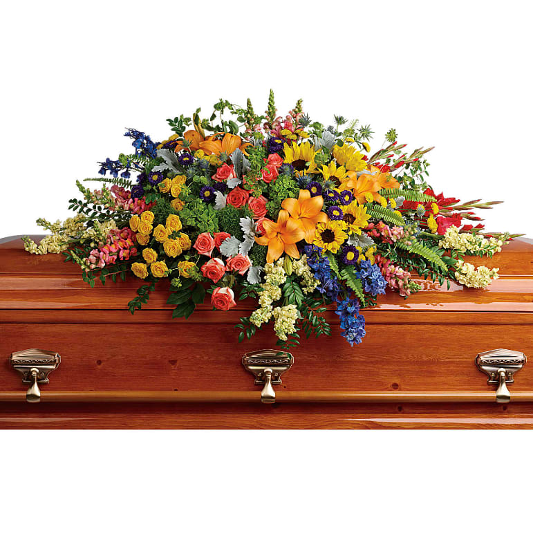 Colorful Reflections Casket Spray - Full of light and love, this colorful casket spray celebrates a bright life with the natural beauty of hydrangea, roses, lilies and sunflowers. Green hydrangea, orange roses, yellow spray roses, orange asiatic lilies, red gladioli, large yellow sunflowers, blue delphinium, orange snapdragons, light yellow stock, purple matsumoto asters, and yellow button spray chrysanthemums are accented with green trick dianthus, blue eryngium, bupleurum, dusty miller, huckleberry, sword fern, lemon leaf. Approximately 50&quot; W x 28&quot; H