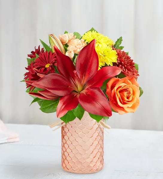 Autumn Confetti™ Bouquet - Our Autumn Confetti bouquet is a celebration of fall color. Warm orange and yellow blooms are loosely gathered with peach roses for a touch of sweetness. Adding to the charm is our new peach quartz mason jar, a textured container designed in a honeycomb pattern and finished with a raffia bow. For cheering on, cheering up or just connecting, it’s a gift full of joy and brightness.