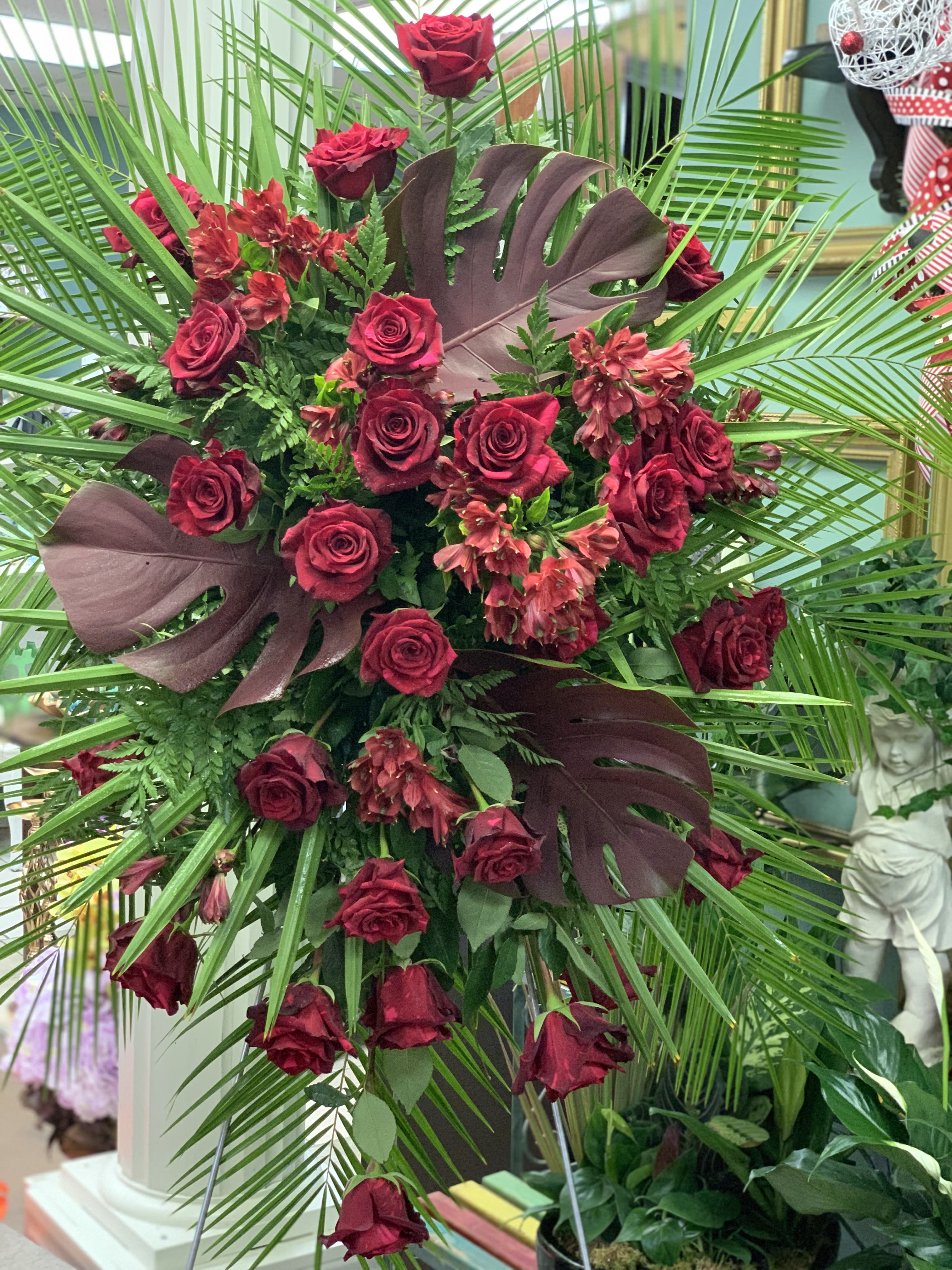 Maroon Memories Maroon Memories - This large funeral tribute features magnificent maroon tropical leaves, fan palm, red roses and more. This is a definate eyecatcher.