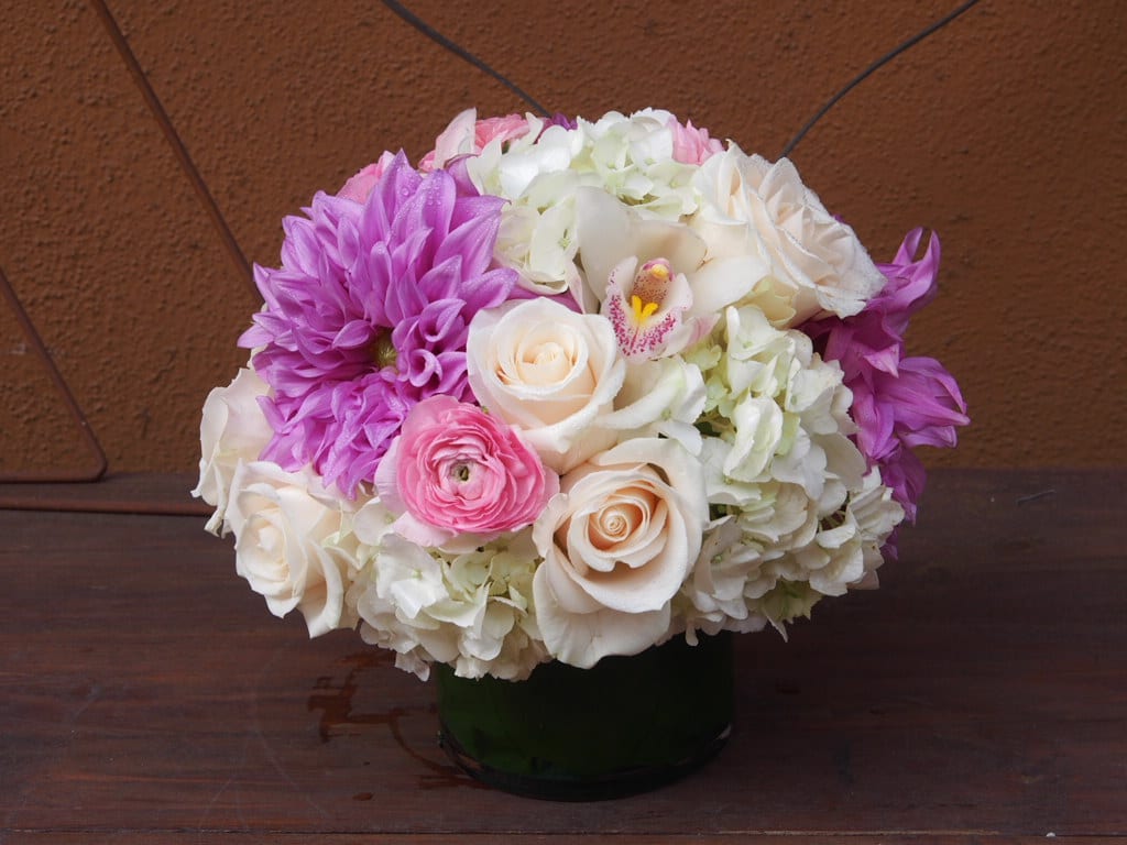 Charmed Charmed - Mix of pastel color flowers, lavender and pinks. Roses, ranunculus, dahlias and hydrangeas in 5" clear glass cylinder.