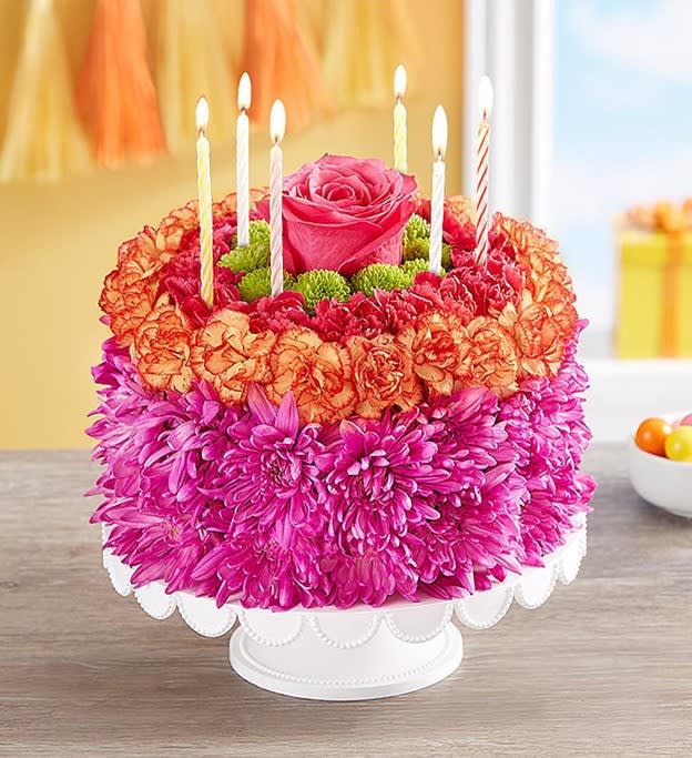 Birthday Wishes Flower Cake - EXCLUSIVE If you want their birthday to be the brightest day of the year, your wish has come true! Our vibrant new flower cake has all the ingredients for a happy celebration: hot pink and fiery orange blooms—and candles to top it off. This confection-inspired creation is the perfect centerpiece for their party. Dial up the fun by adding a balloon to your gift.