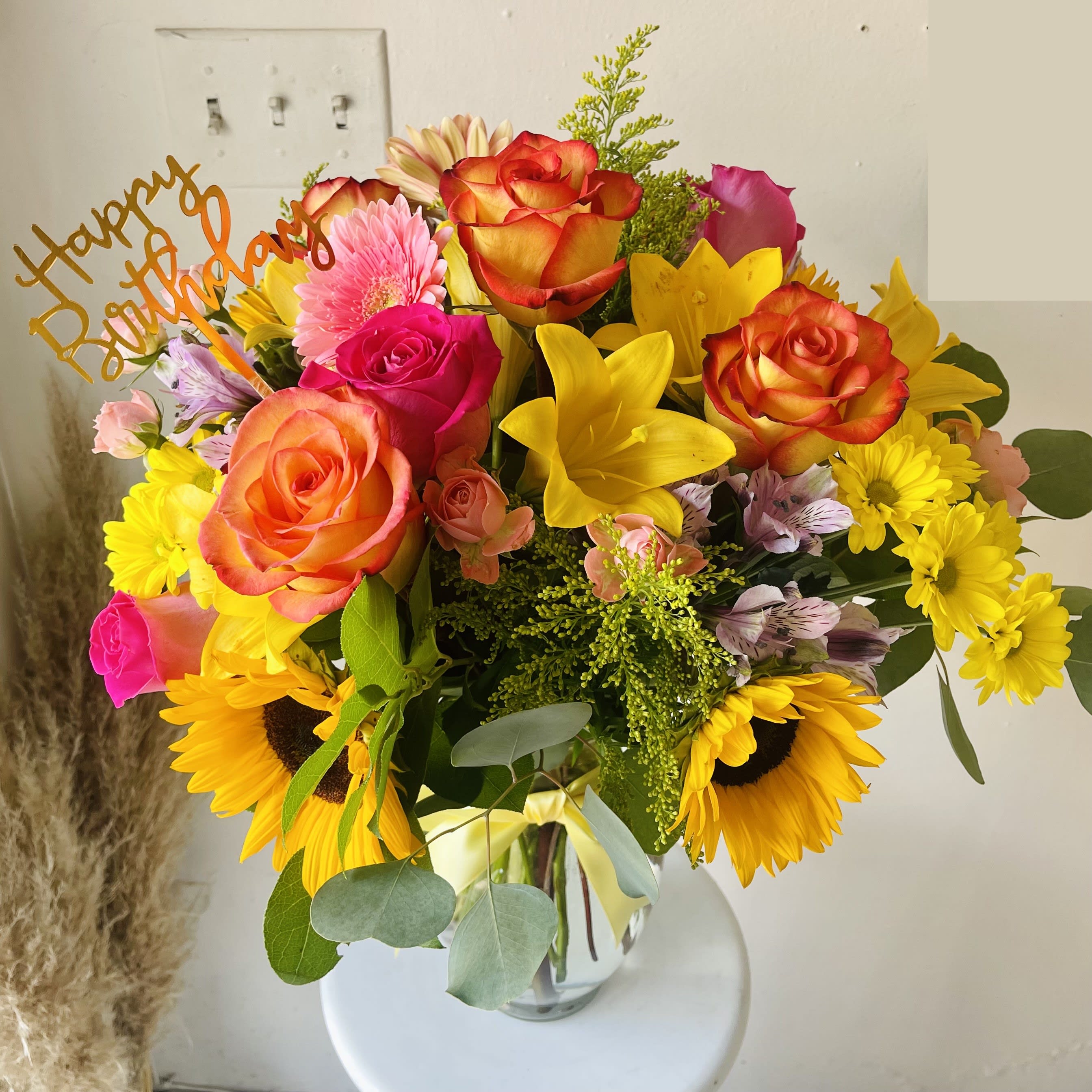 Sun Joy Bouquet - A bright arrangement of roses, sunflowers, lilies, gerbera daisies, alstroemeria, solidago, and greenery in a clear glass vase.  Dressed with a yellow satin ribbon.  Our florists hand-design each arrangement, so colors and varieties may vary due to availability.