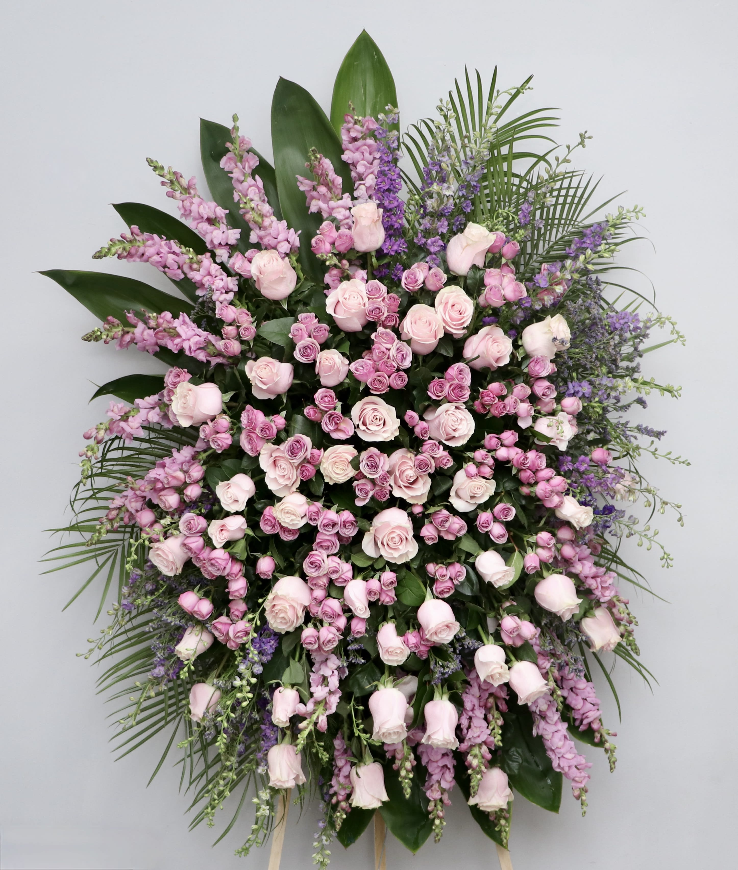 Pink and Lavender Spray  - This spray contains a mix of pinks and lavender. All surrounded by seasonal greens.  We include easel, printed banner and delivery (some fees may apply).  Standard size is 30'' wide, deluxe is 36'', and premium is 42''.