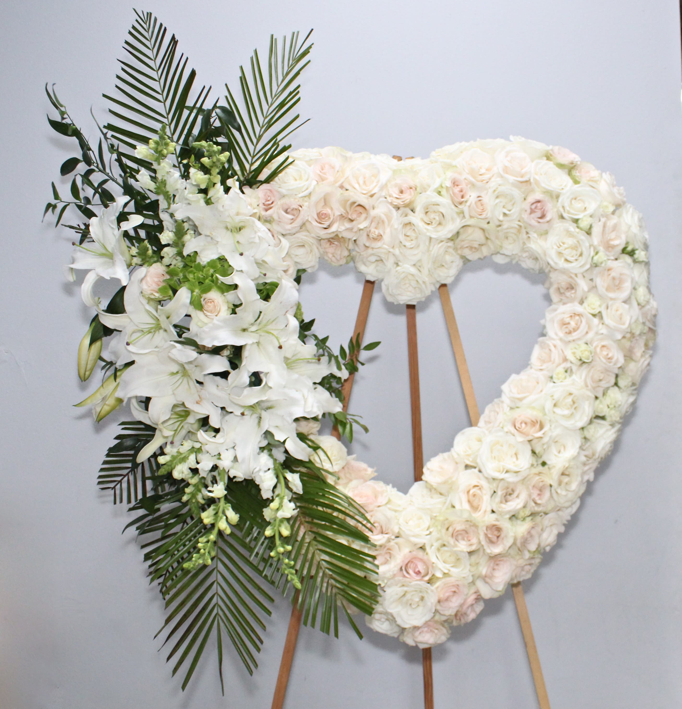Open Heart with Stargazers  - The white heart is made up of white roses, stargazer lilies and seasonal greens.   We include easel, printed banner and delivery (some fees may apply).  Standard size is 30'', deluxe is 36'', and premium is 42''.