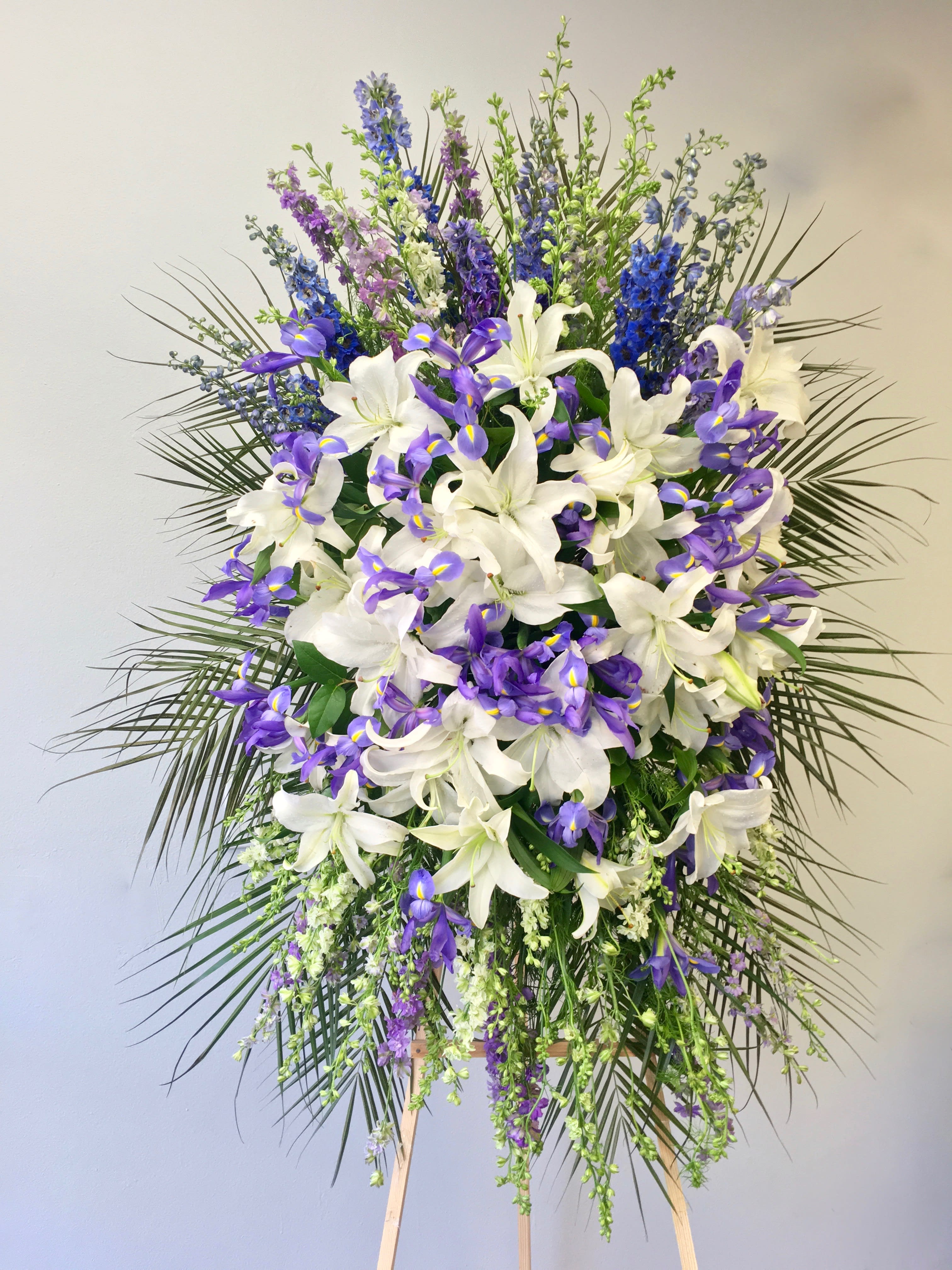 Lavender Iris Spray  - This spray includes a mix of lavender and purple florals, as well as bright stargazer lilies.   We include easel, printed banner and delivery (some fees may apply).  Standard size is 30'' wide, deluxe is 36'', and premium is 42''.