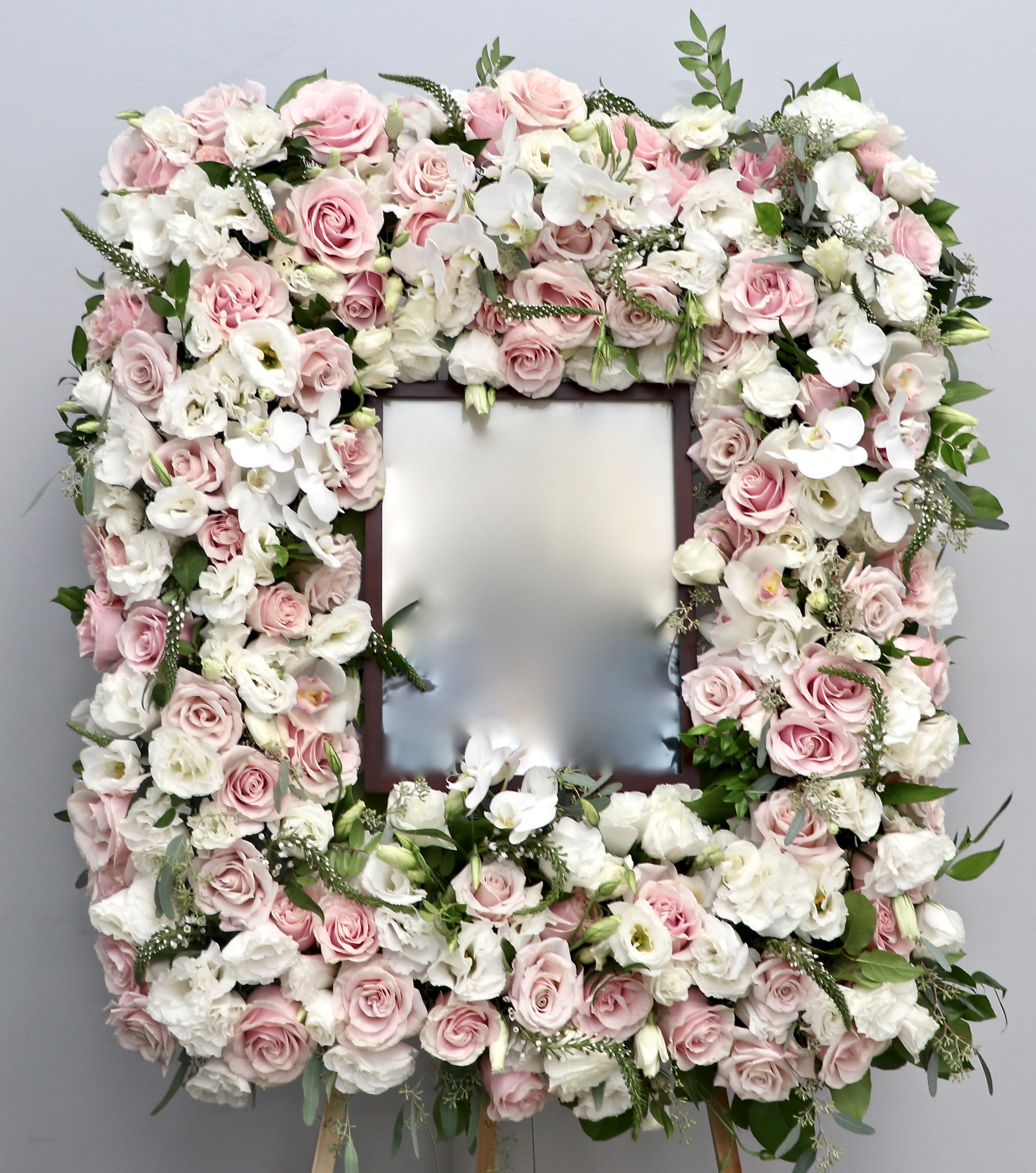 Pink Frame  - With a mix of white and pink roses, orchids and seasonal greens this sympathy arrangement is approximately 32 inches tall.